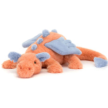 A plush toy depicting a coral-colored dragon with blue wings, ears, spines, and tail dart, lying on a plain background.