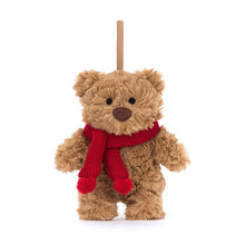 A stuffed toy bear with a knitted red scarf and toffee ribbon loop for hanging, dressed in toffee fur color.