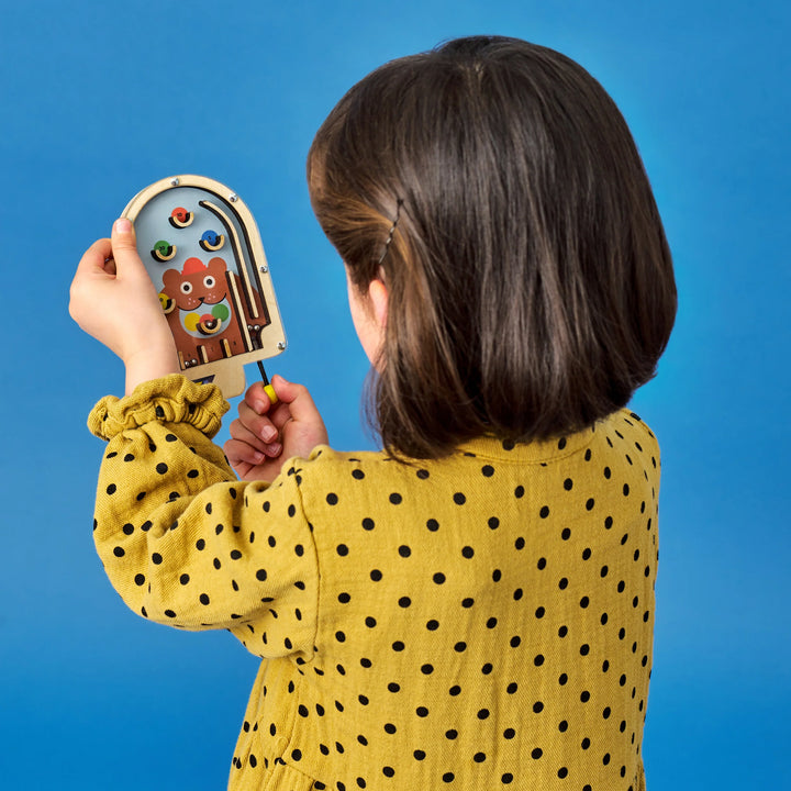 Young girl playing with wooden KIDOKI pinball game