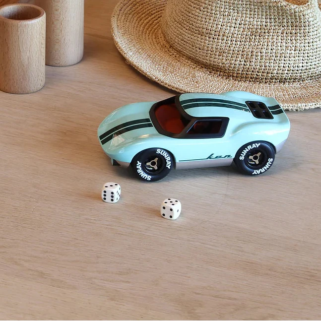 Dice and  light blue racing car toy on a wooden table