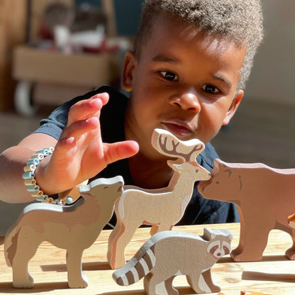 Child playing with wooden animal toys on a table