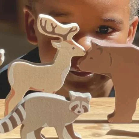 Child playing with wooden animal toys on a wooden surface