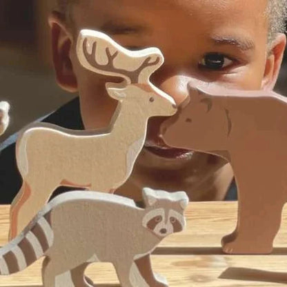 Child playing with wooden animal toys on a wooden surface