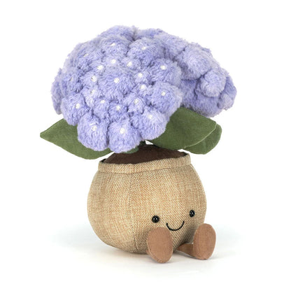 Plush toy resembling a  blue hydrangea plant with green leaves and brown fabric pot with a smiling face on a white background