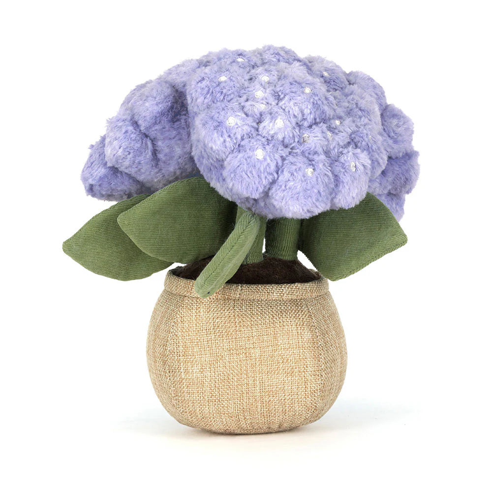 Stuffed toy flower with purple flowers and green leaves in a beige pot on a white background