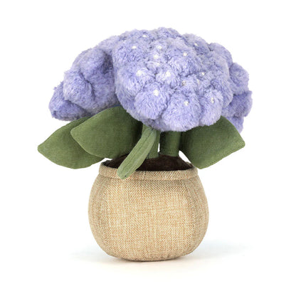 Stuffed toy flower with purple flowers and green leaves in a beige pot on a white background