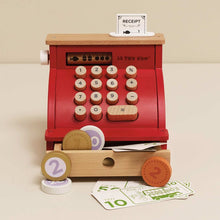 Wooden toy cash register with buttons and a receipt on a beige background
