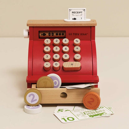 Wooden toy cash register with buttons and a receipt on a beige background