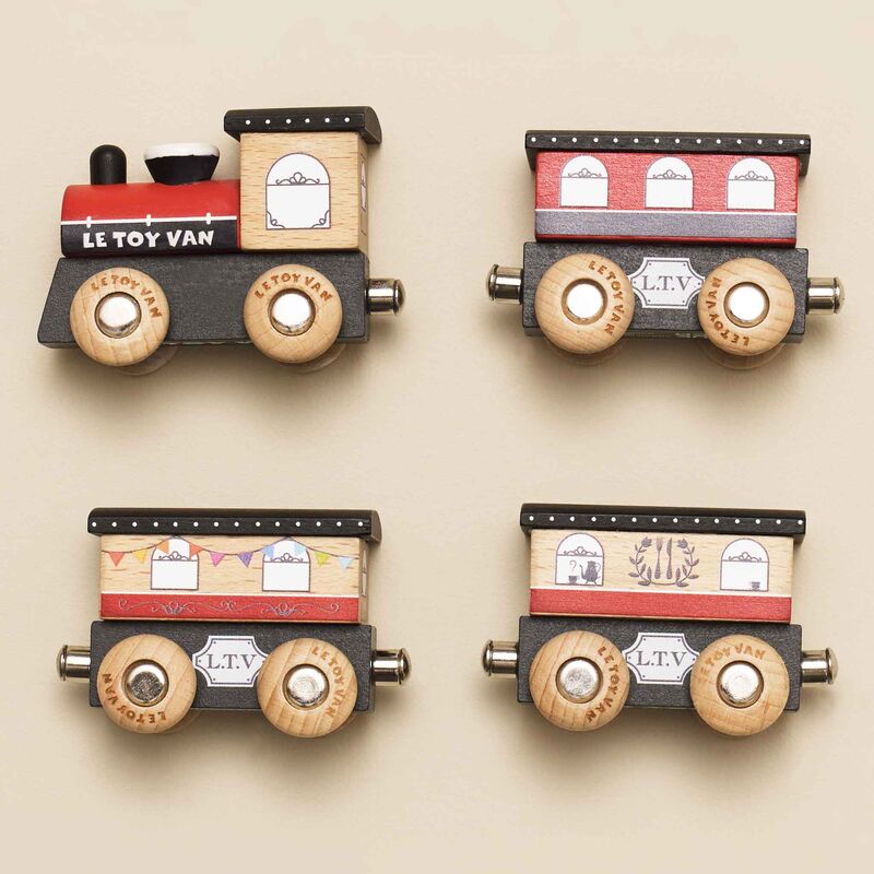 Four wooden toy train cars with 'Le Toy Van' branding on a beige background