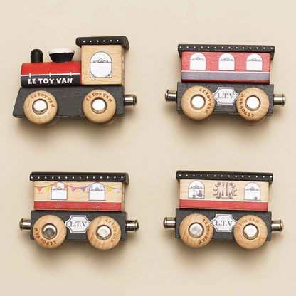 Four wooden toy train cars with 'Le Toy Van' branding on a beige background