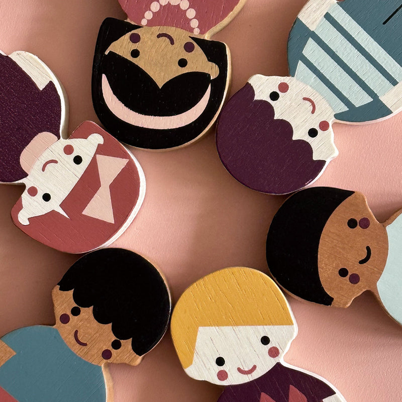 Colorful wooden toy faces on a pink background