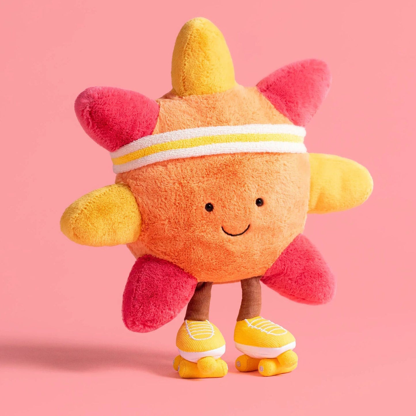 Plush toy resembling a sun with pink rays on a pink background