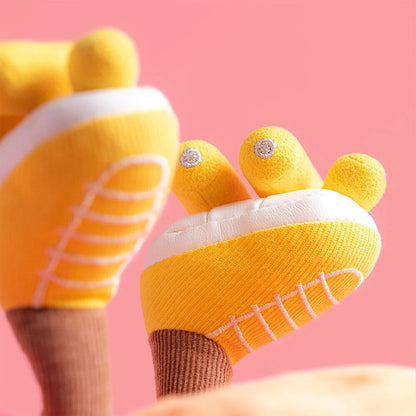 Yellow baby like shoes with white soles on a pink background