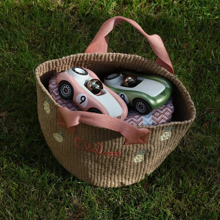 Toy cars in a decorative basket on grass