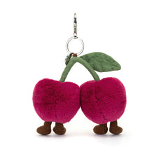 A plush cherries bag charm with green leaves, brown stems, and a silver clasp.