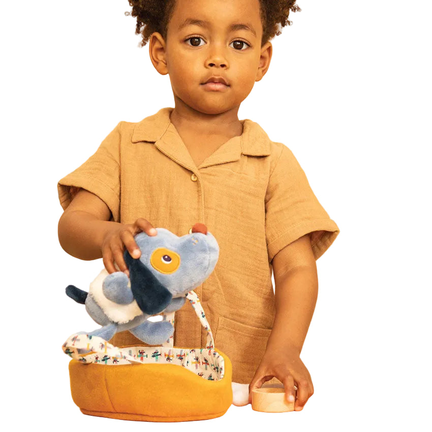 Child playing with a blue toy  with a yellow fabric carry basket on a white background