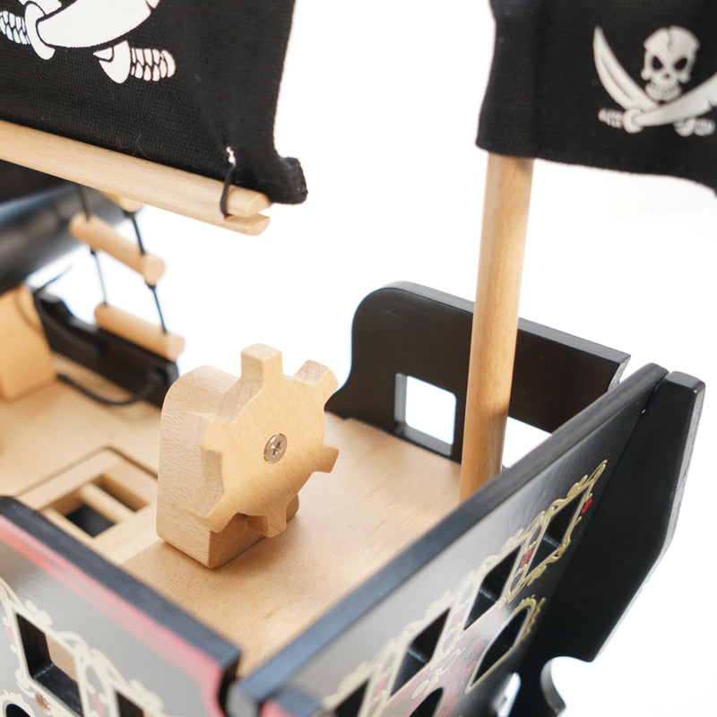 Close-up of a toy pirate ship with a wooden gear on a white background