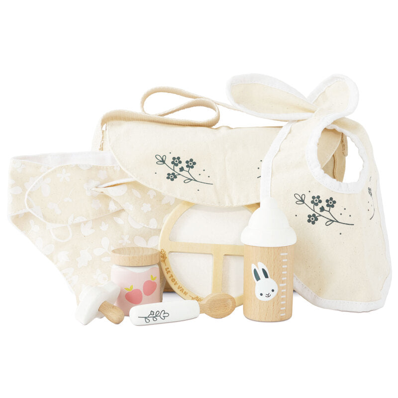 A doll nursing set including a pacifier, bottle, spoon, feeding plate, cloth nappy, cloth bib, and a shoulder bag, all in pastel colors.