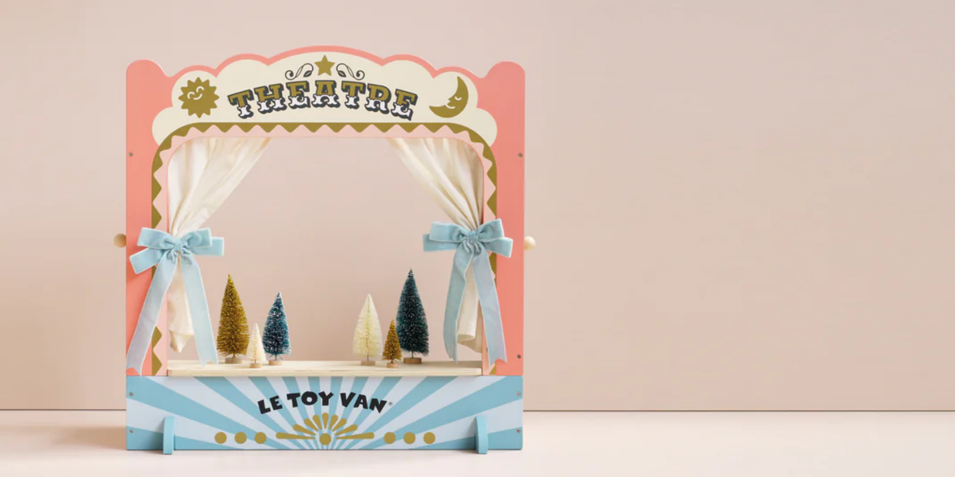 Toy theatre set with curtains and trees on a pink background, featuring the brand 'Le Toy Van'.