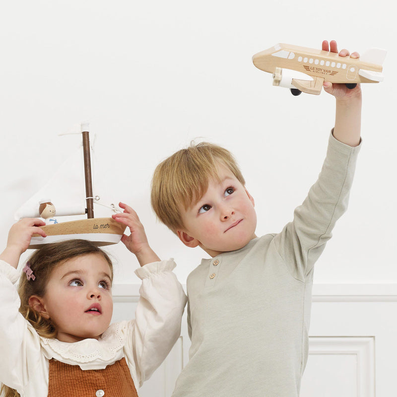 Two children playing with wooden toys against a white background