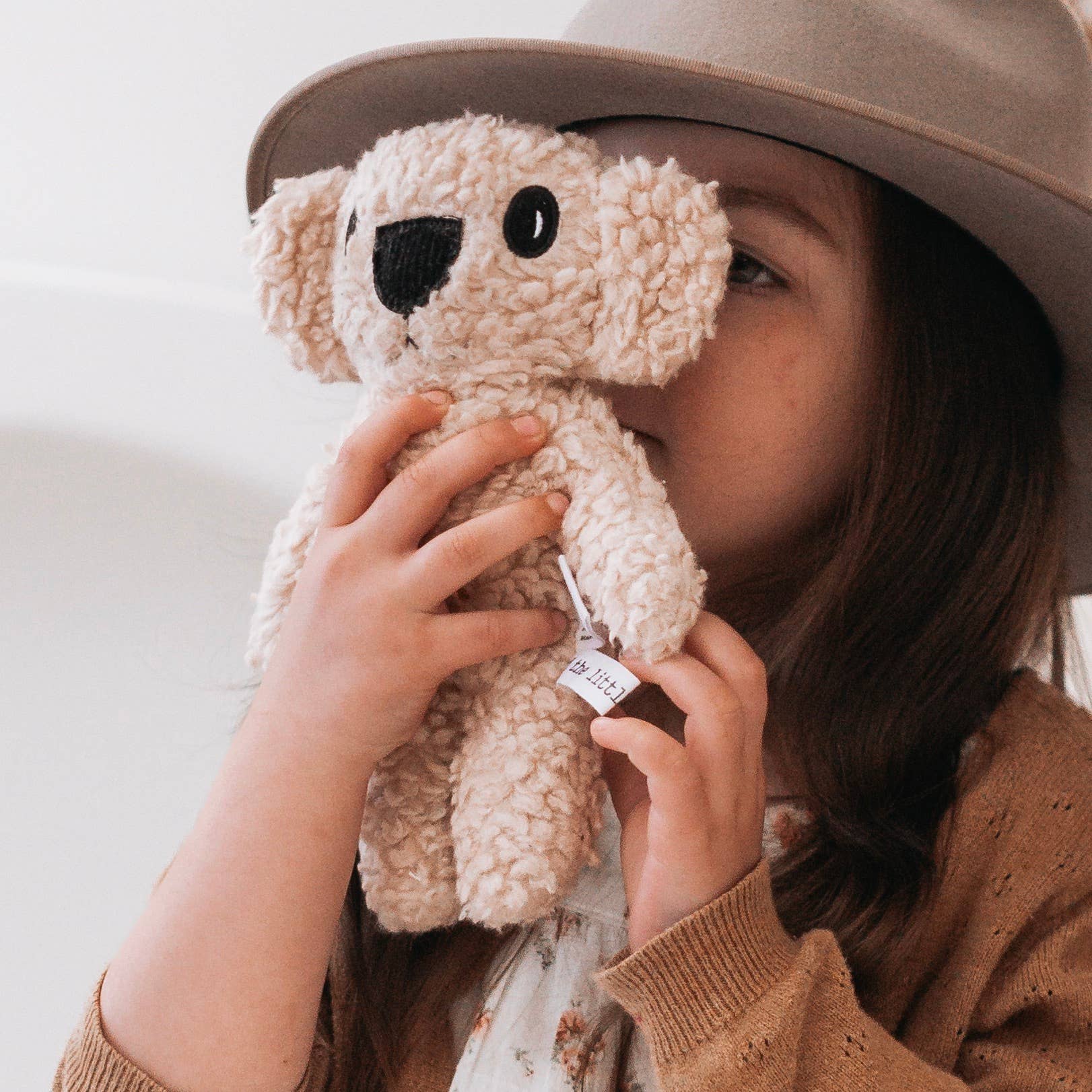 Person holding a beige teddy bear with a neutral background