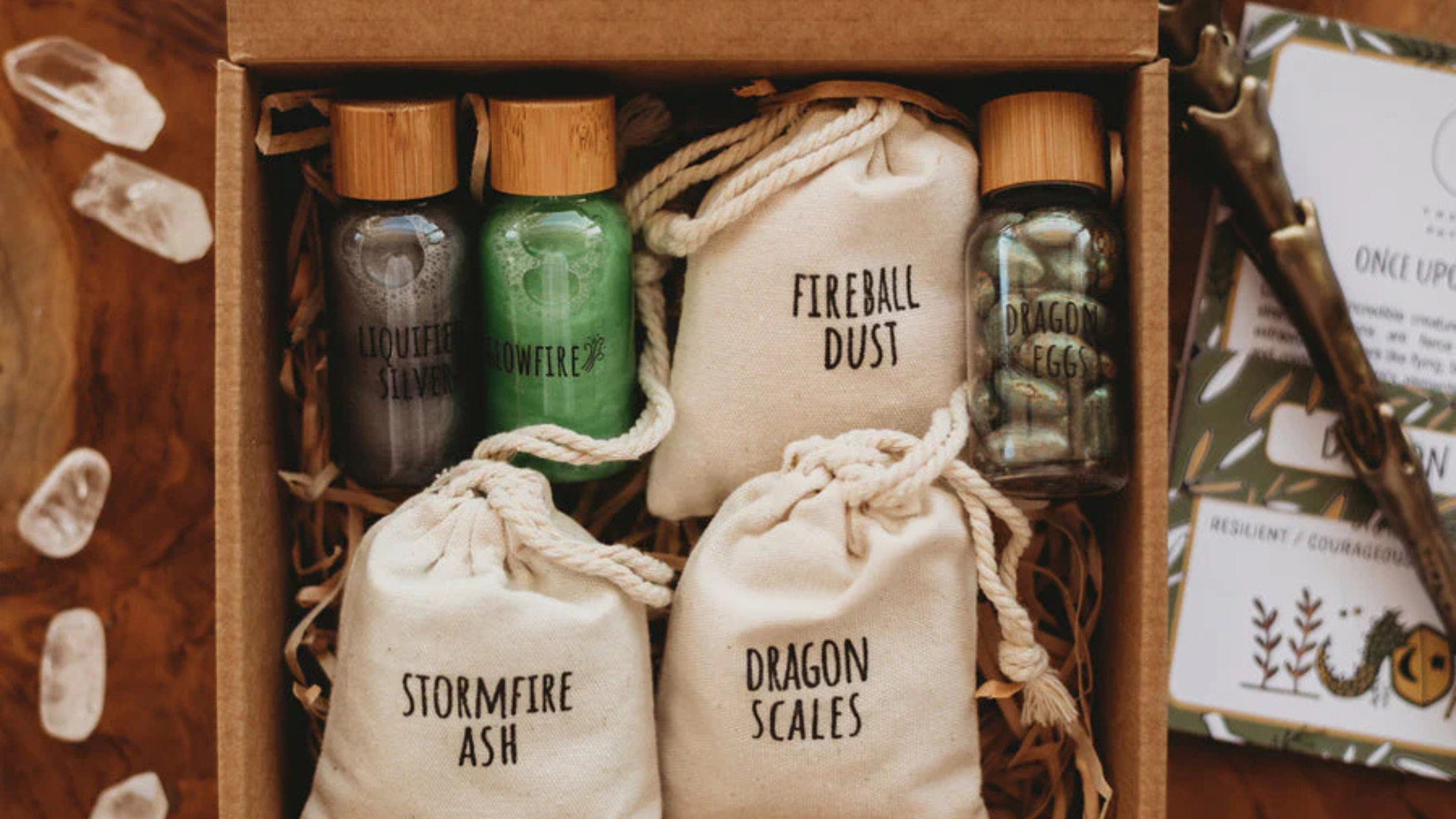 Wooden box with labeled bags containing fantasy-themed items like 'Fireball Dust' and 'Dragon Scales'.