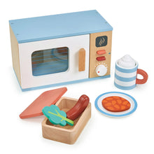 Wooden toy microwave set with a cup, plate, and Tupperware-style box and lid containing play food items like a sausage, baked beans, and broccoli.