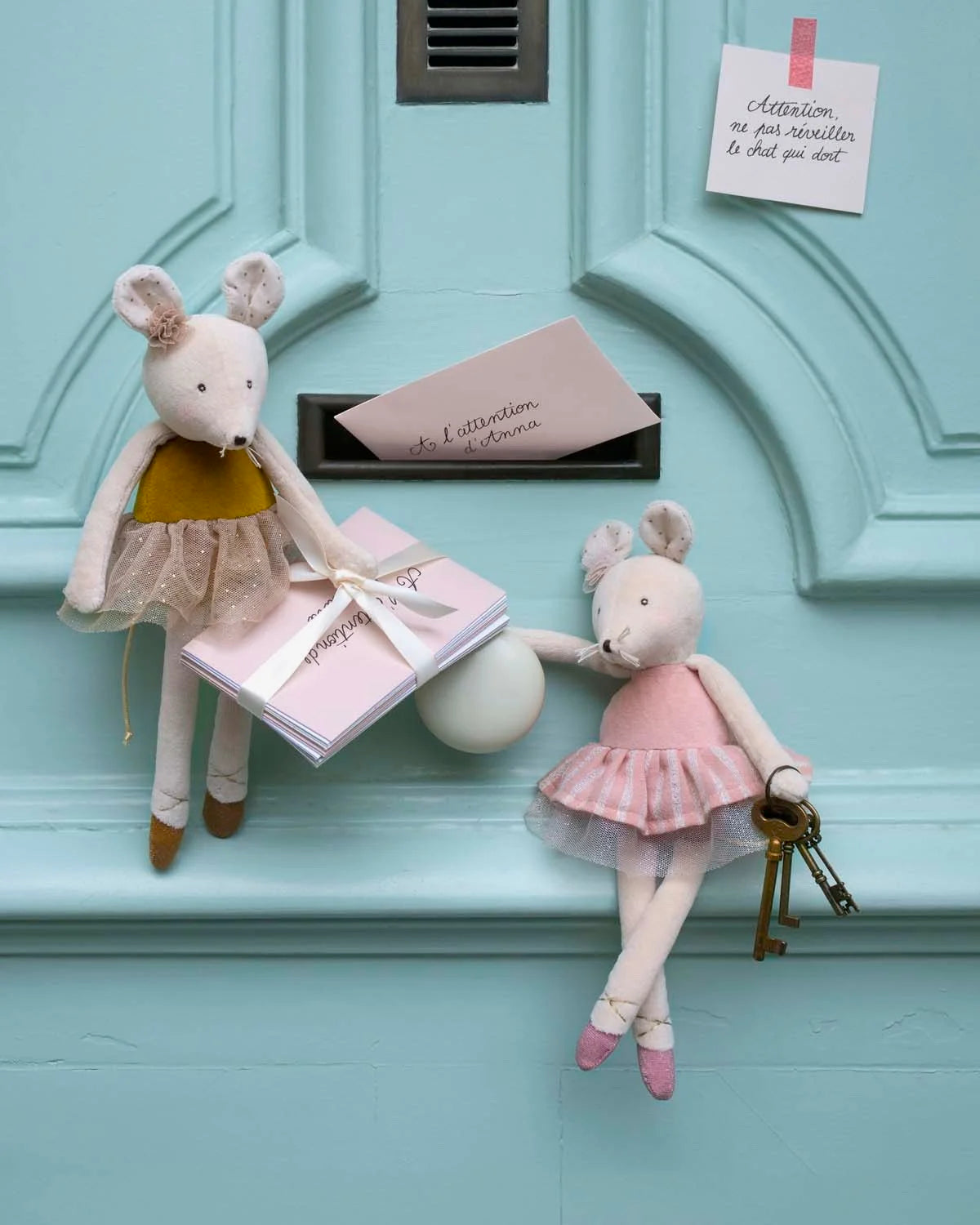 Two plush mouse dolls on a light blue door with a key and card.