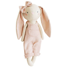A pink Olivia Bunny doll with beige ears and a bow on its head, dressed in a linen overalls.