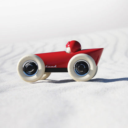 Red toy Playforever car  on a white sand background