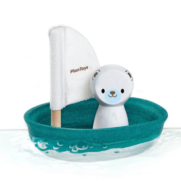 Teal green wooden dinghy boat toy with white fabric mast and cute wooden white polar bear figure.