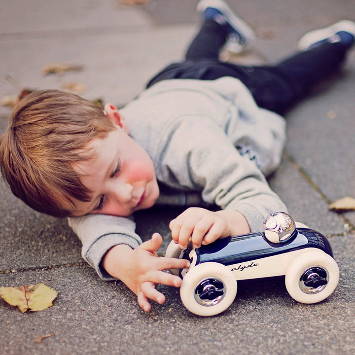 Child playing with a toy car on a pavement