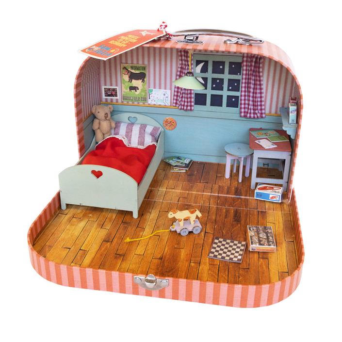 A portable dollhouse with a pink and white striped suitcase-style case, containing a bedroom setup with wooden furniture, a miniature teddy bear, and decorative stickers.