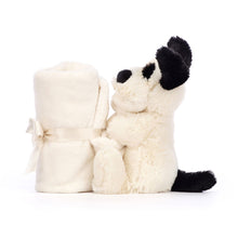 A plush toy depicting a black and cream colored puppy with a soft, white blanket.