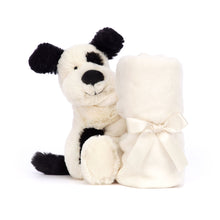 A plush toy depicting a black and cream colored puppy with a soft, white blanket.