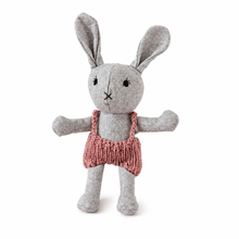 A grey felt stuffed bunny doll wearing a pink knitted romper, standing against a plain white background.