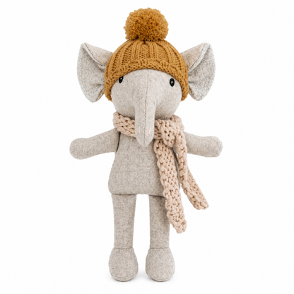 Grey elephant soft toy with mustard yellow knitted hat and light tan scarf, against a white background.