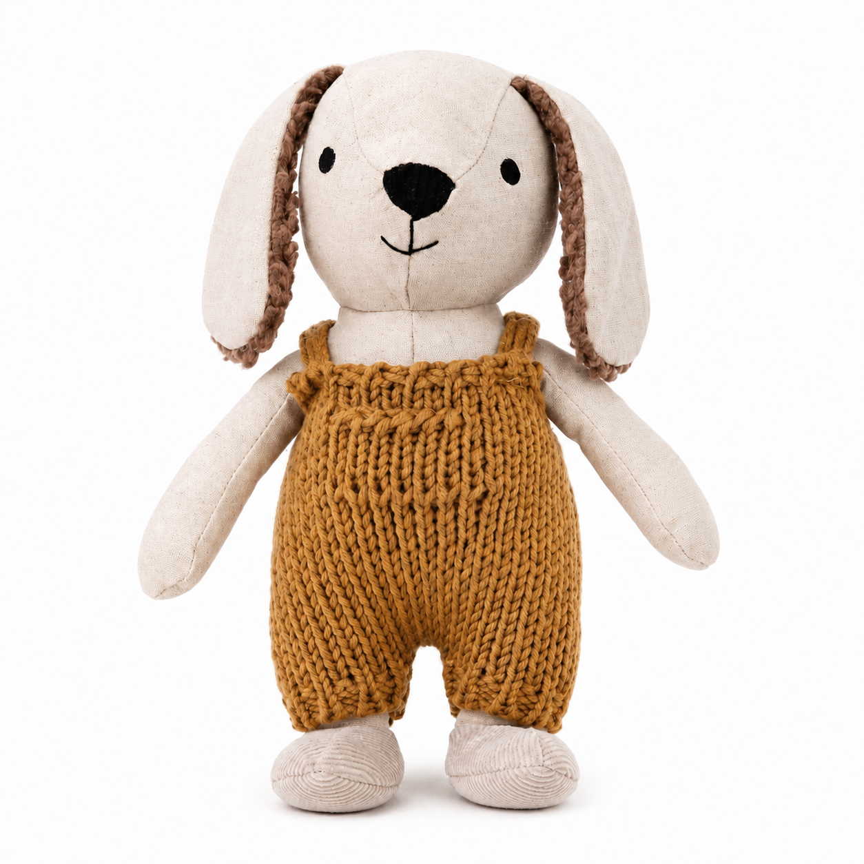 A plush stuffed dog toy with long cream-colored ears, brown textured inner ears, a black embroidered nose and mouth, and a mustard-yellow knitted overall-style body, shown on a plain white background.