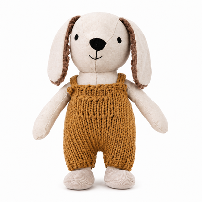 A plush stuffed dog toy with long cream-colored ears, brown textured inner ears, a black embroidered nose and mouth, and a mustard-yellow knitted overall-style body, shown on a plain white background.