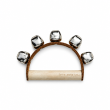 A hand-held tambourine with five silver metal bells on a brown leather arch and a light wood handle, featuring the brand name 'love note co.