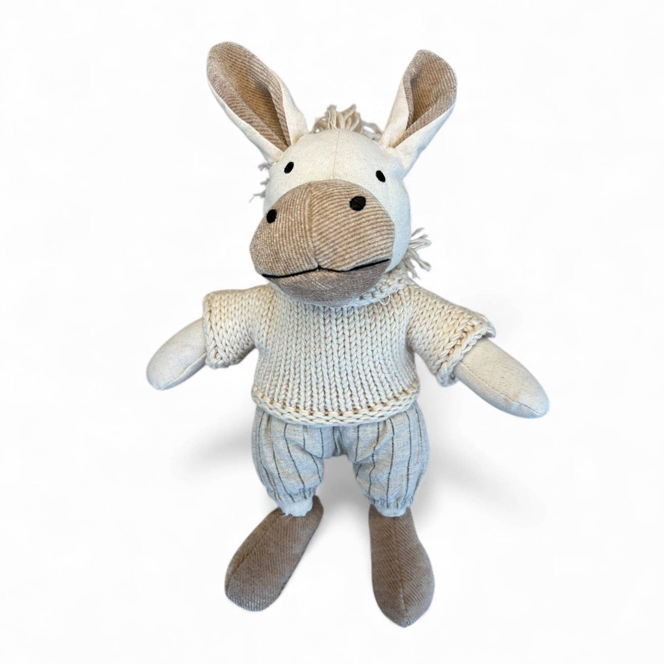 Stuffed donkey toy wearing a knitted sweater on a white background