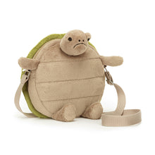 A beige fabric turtle-shaped bag with a green embroidered shell, featuring a silver zipper and a webbed strap.