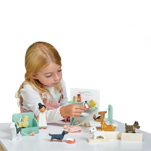 A child playing with a wooden toy set that includes various toy dogs and a grooming salon setup.