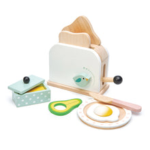 A wooden toaster set with pretend food items including a toasted slice of bread, a poached egg, and sliced avocado, alongside a wooden knife and a butter dish.
