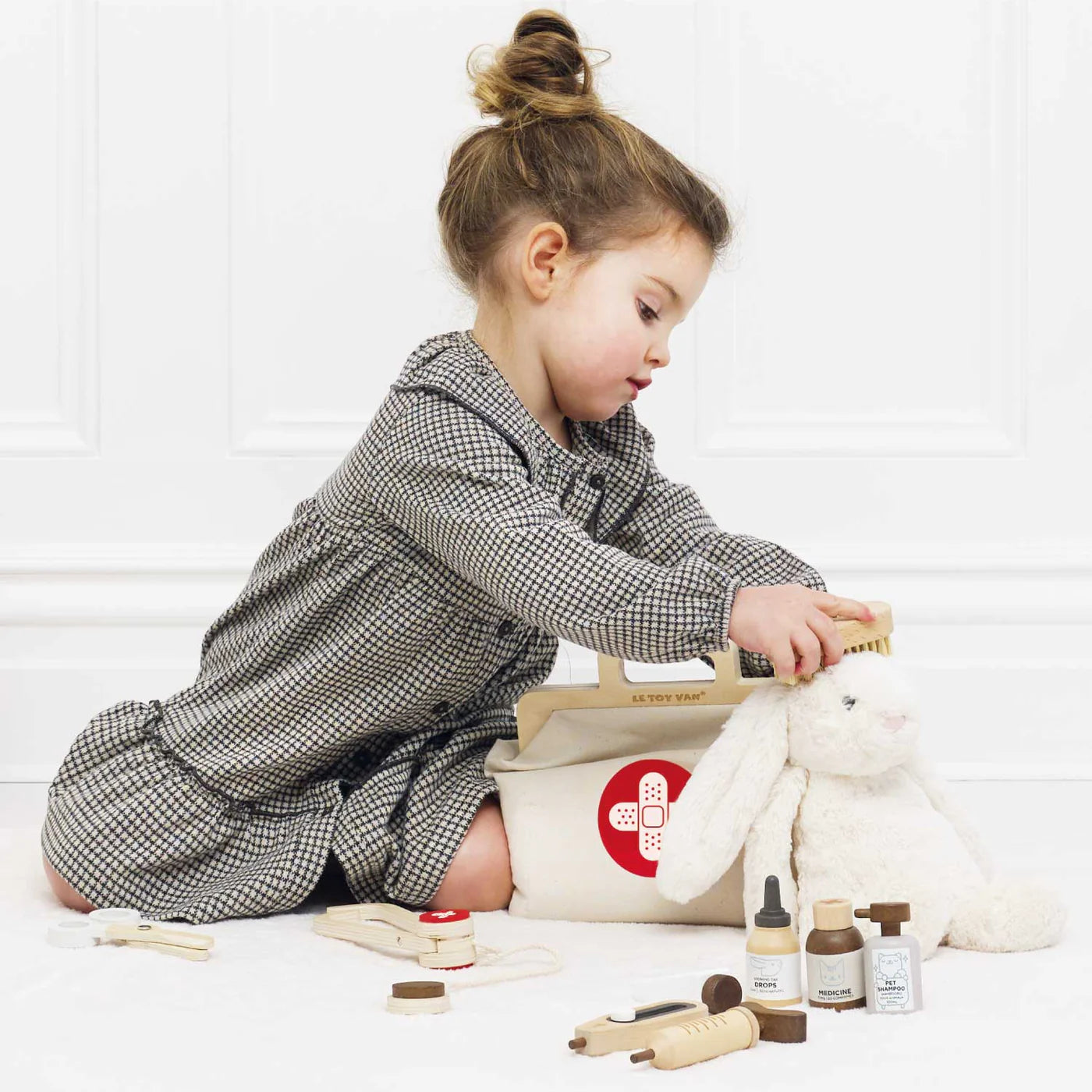 Child playing with toys and a first aid kit on a white floor.