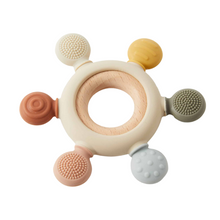 A silicone teether with wooden elements, featuring various textures and soft bristles.