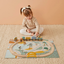A child playing with a wooden train set featuring animal puzzle pieces on a playmat.