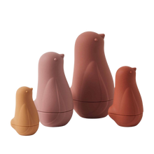 A set of four Chickadee Nesting Dolls in shades of pink and brown, stacked in size order with the smallest on the bottom and the largest on top.