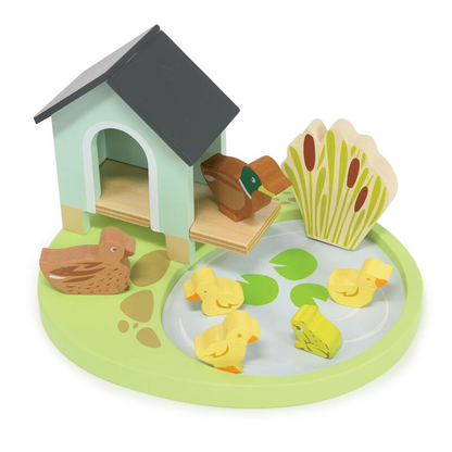 Wooden toy set with a duck house, ducks, and a pond on a white background