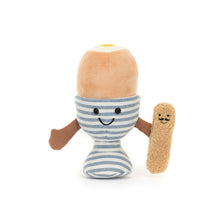 A soft toy resembling a dippy egg in a blue and white stripe egg cup with a brown toast soldier.